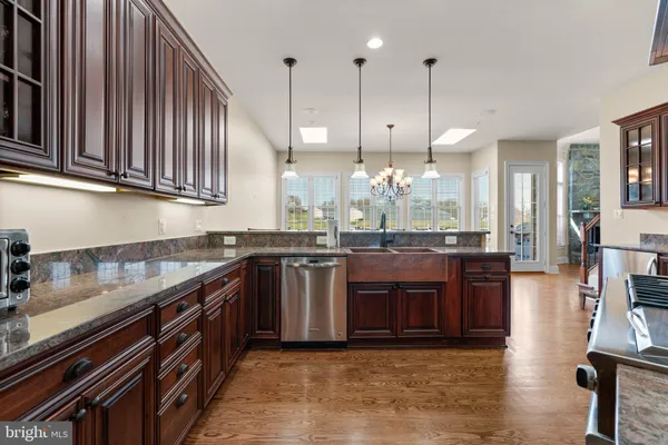 a kitchen with stainless steel appliances granite countertop a stove a sink dishwasher a refrigerator and a oven with wooden floor