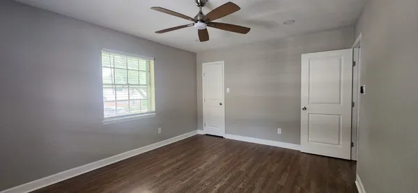 a view of a room with wooden floor and a ceiling fan