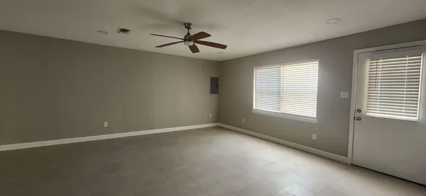 an empty room with a window and a fan