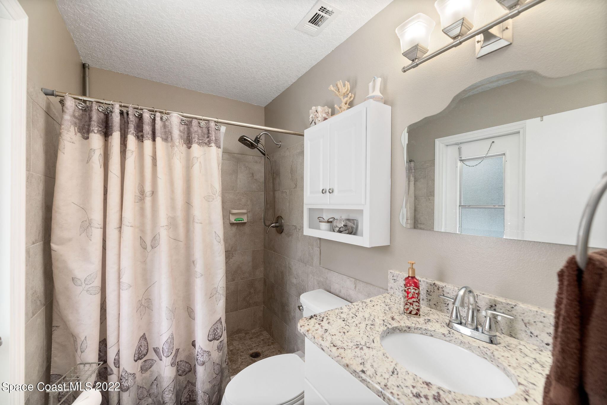 1821 Britt Road Cocoa, FL 32926 - Photo 28 of 63 a bathroom with a granite countertop sink a toilet a mirror a vanity and shower