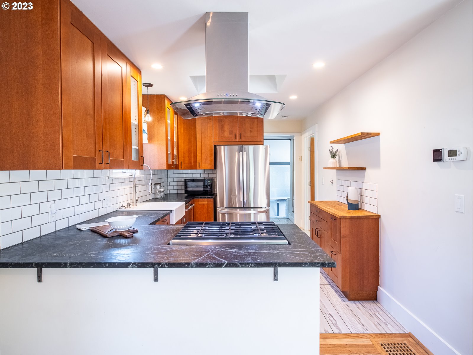 903 North Winchell Street Portland, OR 97217 - Photo 9 of 34 a kitchen with kitchen island granite countertop wooden cabinets a sink dishwasher and a stove with wooden floor
