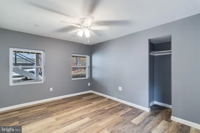 a view of an empty room with window and wooden floor