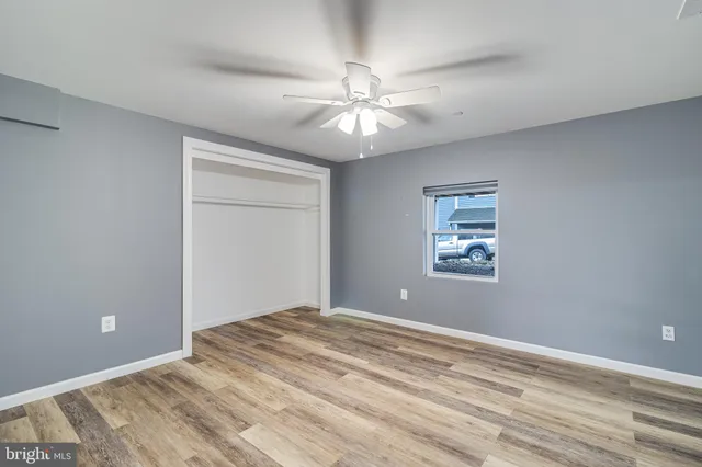 a view of an empty room with window and chandelier fan
