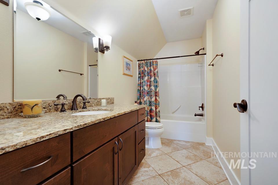8271 Washoe Road Fruitland, ID 83619 - Photo 29 of 29 Bathroom featuring a spacious vanity with a light-toned granite countertop, dark wood cabinetry, an undermount sink with an oil-rubbed bronze faucet, and a shower-over-tub combination with matching fixtures