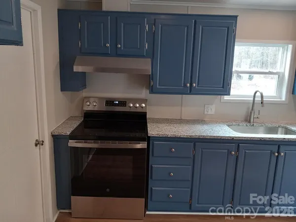 a kitchen with granite countertop wood cabinets and a stove top oven