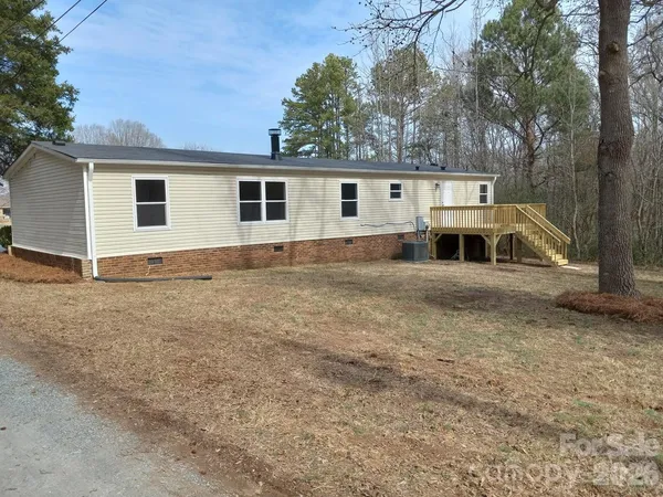 a view of house with backyard and trees in the background