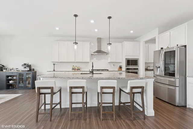 a kitchen with stainless steel appliances kitchen island granite countertop a wooden floor and white cabinets
