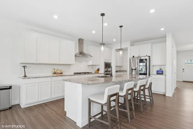 a kitchen with stainless steel appliances kitchen island granite countertop a wooden floor and white cabinets