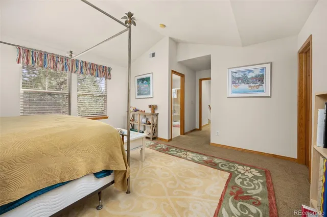 a bed sitting in a spacious bedroom next to a window