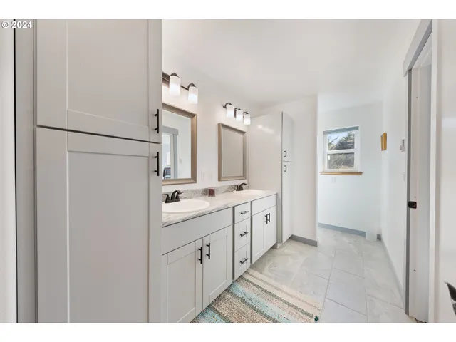 a large bathroom with a double vanity sink a toilet and a shower