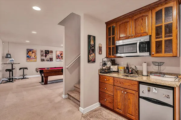 a open kitchen with stainless steel appliances granite countertop a stove top oven a sink a dining table and chairs with wooden floor