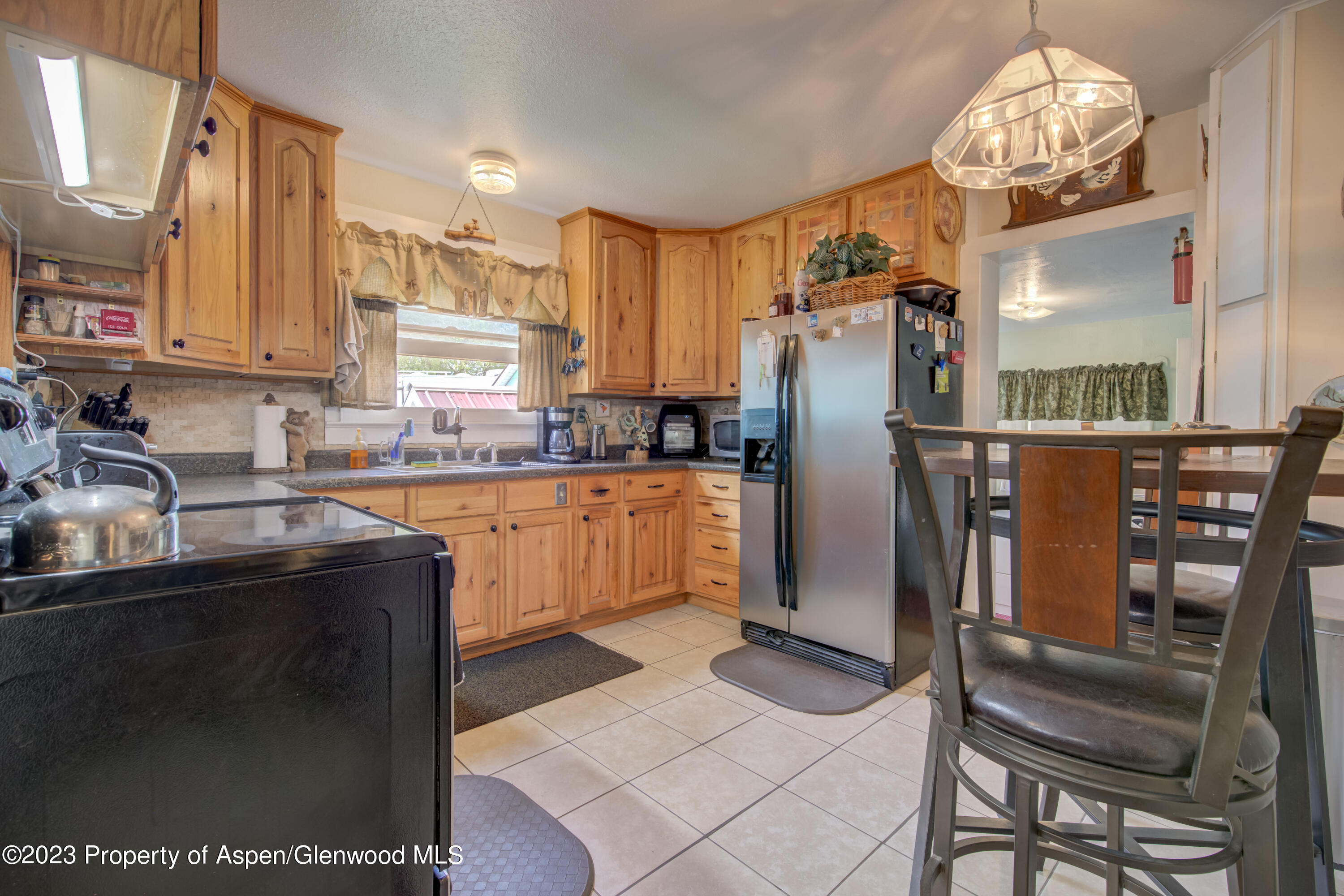 690 Pershing Street Craig, CO 81625 - Photo 32 of 72 a kitchen with stainless steel appliances granite countertop a refrigerator a sink dishwasher a stove a dining table and chairs with wooden floor