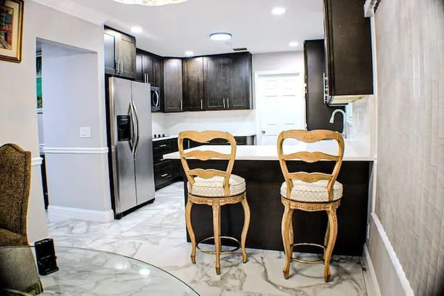 a kitchen with stainless steel appliances kitchen island granite countertop a refrigerator and a wooden cabinets