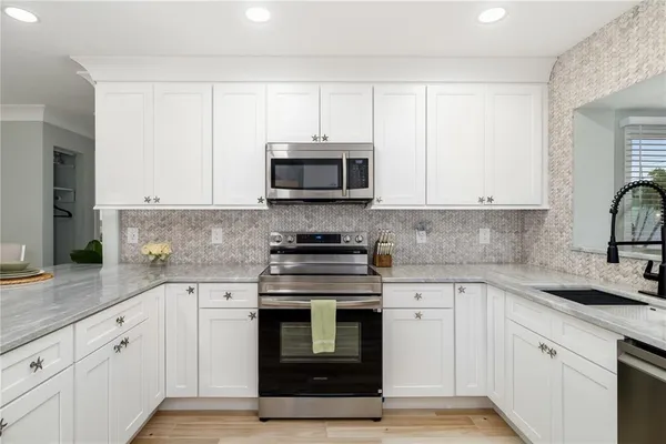 a kitchen with granite countertop white cabinets and stainless steel appliances