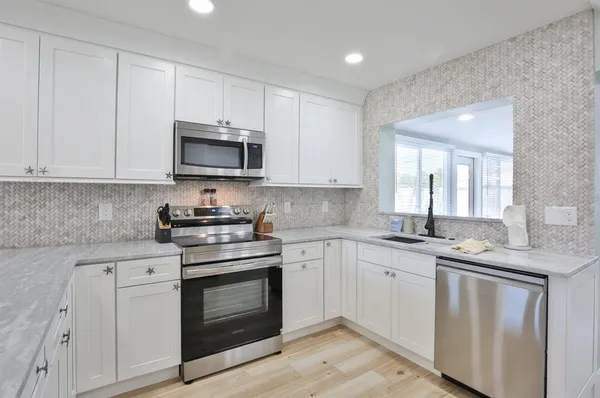 a kitchen with granite countertop white cabinets and stainless steel appliances