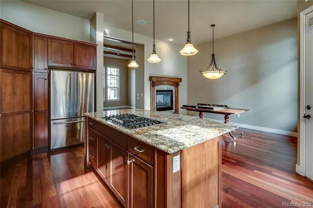 a kitchen with stainless steel appliances granite countertop a refrigerator a stove and a wooden floors