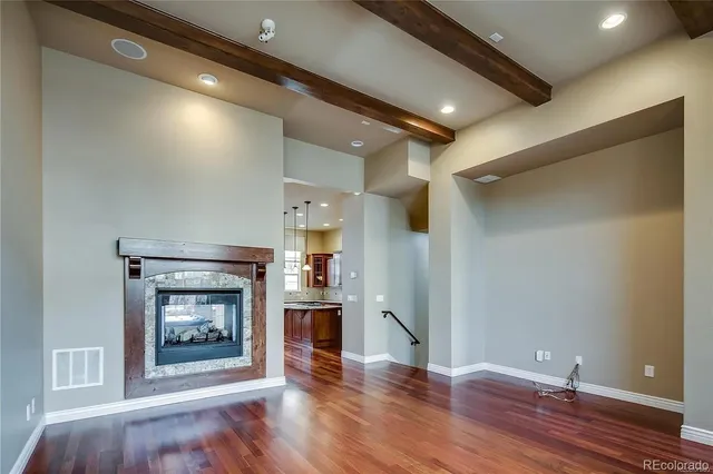 a view of an empty room with wooden floor a fireplace and a window