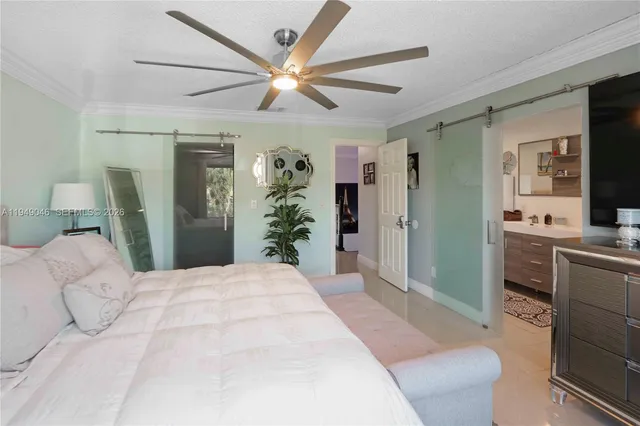a spacious bedroom with a large bed a flat tv screen and a chandelier