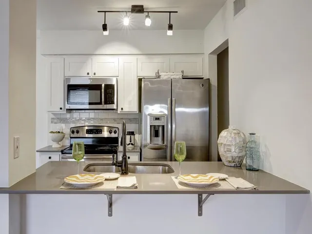 a kitchen with stainless steel appliances granite countertop a refrigerator a stove top oven a sink and dishwasher