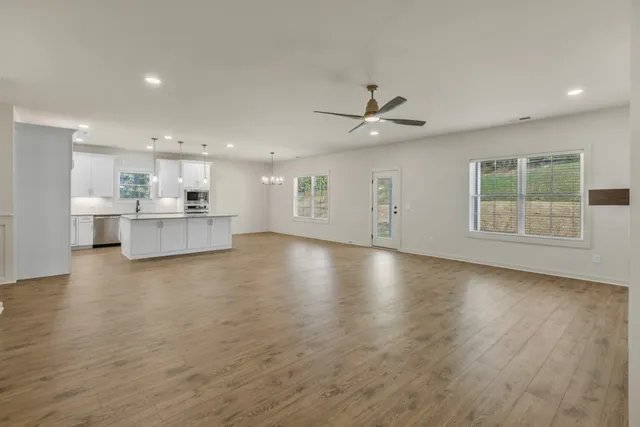 an empty room with wooden floor and a ceiling fan