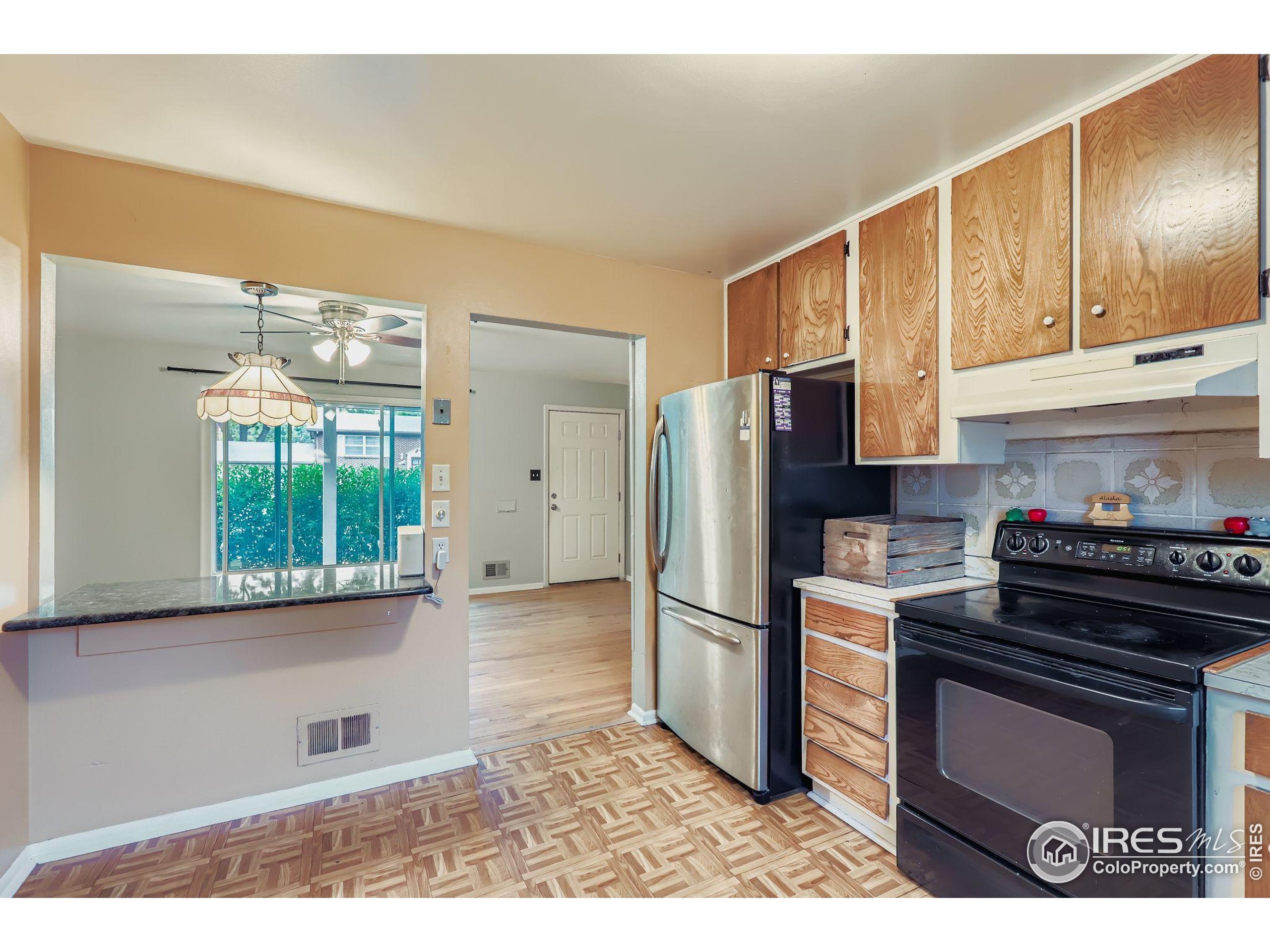 11816 Spring Drive Northglenn, CO 80233 - Photo 4 of 10 a kitchen with granite countertop a stove a refrigerator and a stove top oven