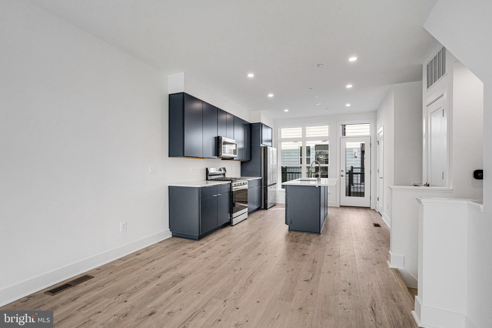 2058 Tysons Ridgeline Road Falls Church, VA 22043 - Photo 19 of 48 a kitchen with stainless steel appliances a refrigerator a stove top oven and wooden floor