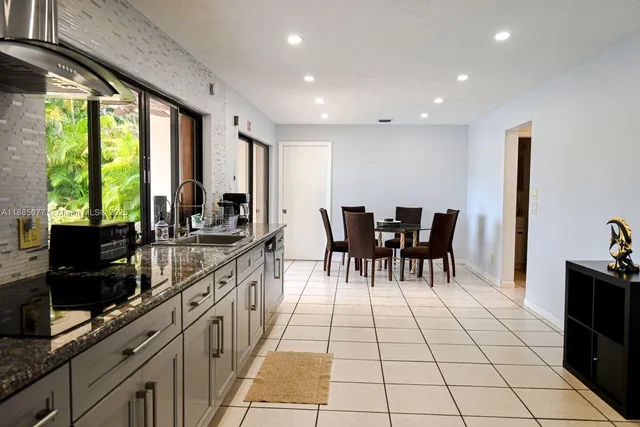 a kitchen with granite countertop a sink dining table and chairs