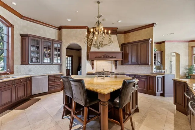 a kitchen with granite countertop a dining table chairs cabinets and stainless steel appliances