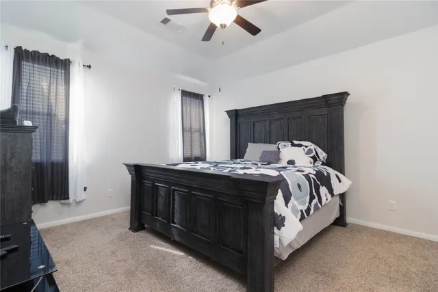 a bed sitting in a spacious bedroom next to a window and a chandelier