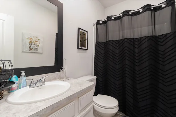 a bathroom with a granite countertop bathtub sink vanity mirror and toilet