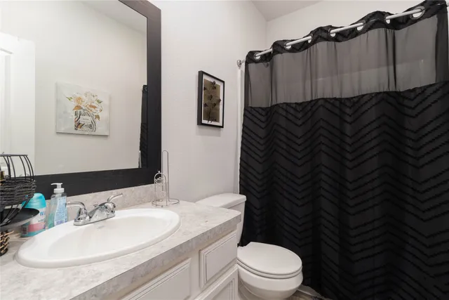 a bathroom with a granite countertop bathtub sink vanity mirror and toilet