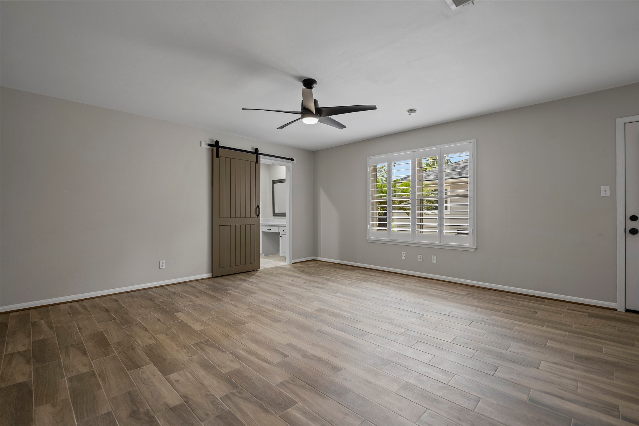 6507 Allentown Drive Spring, TX 77389 - Photo 8 of 30 Light-filled and spacious primary suite featuring plantation shutters, an elegant ceiling fan, and a door opening to the patio.