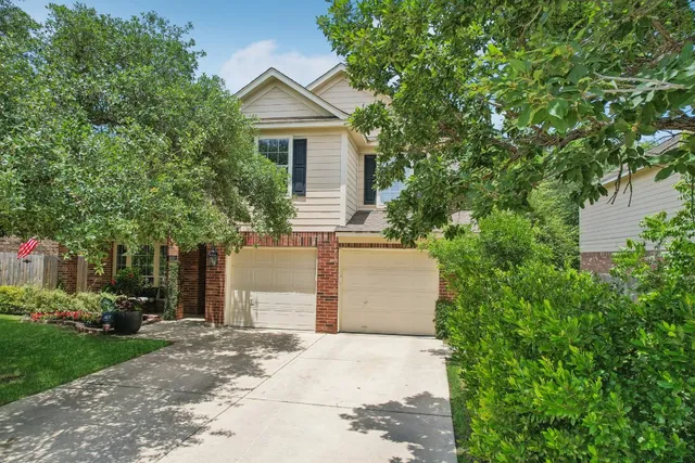 a view of a house with a yard and large tree