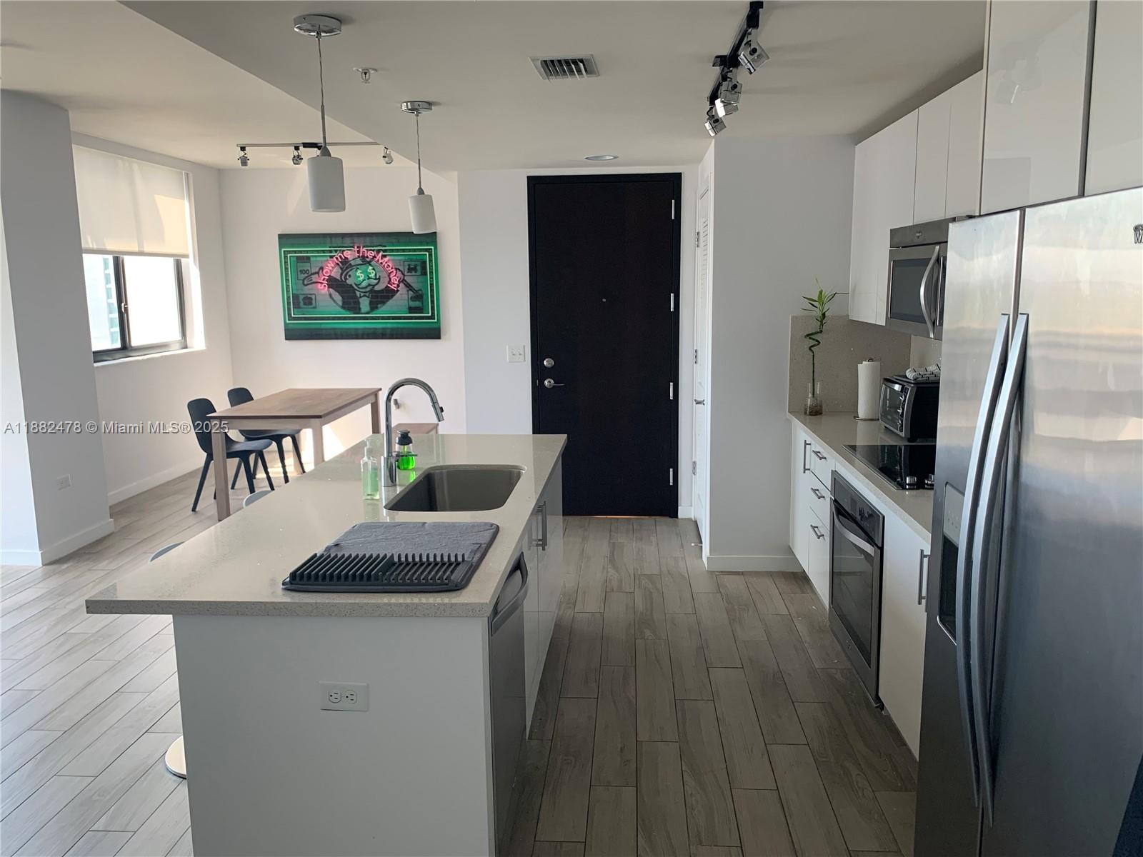 999 Southwest 1st Avenue, Unit 1703 Miami, FL 33130 - Photo 2 of 28 a kitchen with kitchen island a counter top space a sink a refrigerator and a stove