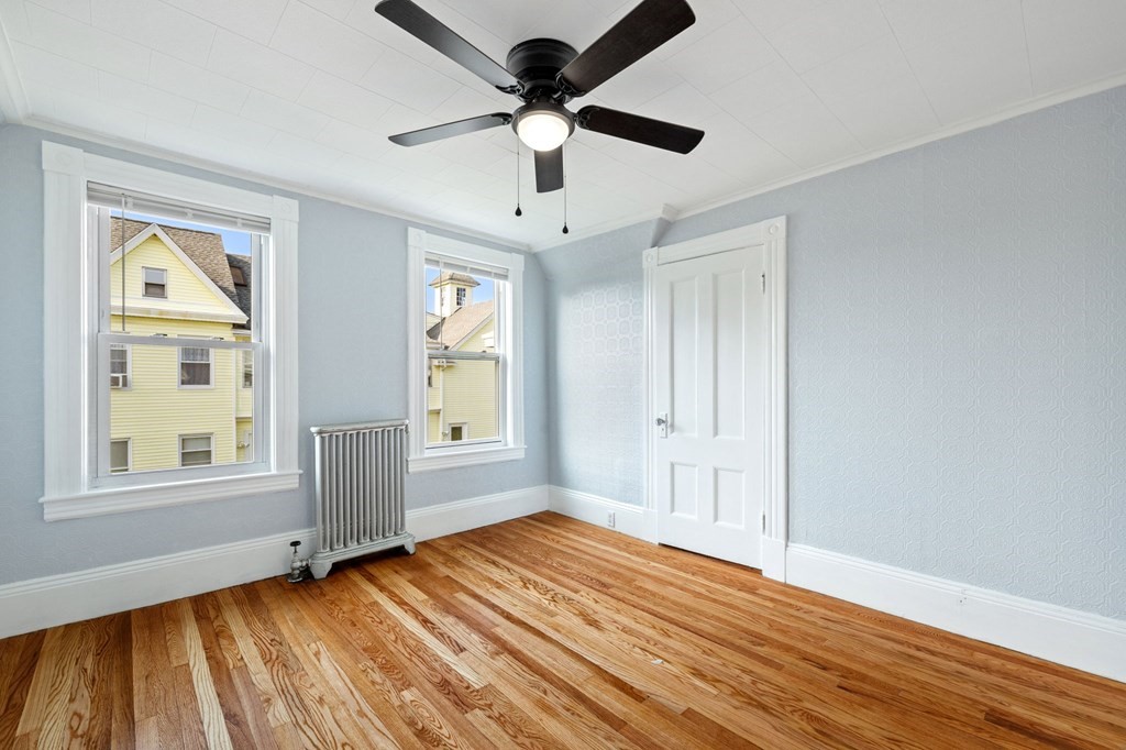 253 Mammoth Road Lowell, MA 01854 - Photo 23 of 42 an empty room with wooden floor chandelier fan and windows