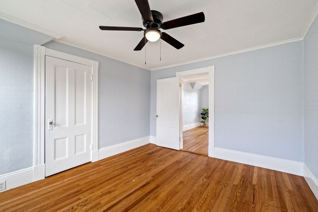 253 Mammoth Road Lowell, MA 01854 - Photo 24 of 42 a bedroom with wooden floor ceiling fan and window
