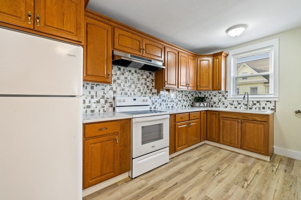 253 Mammoth Road Lowell, MA 01854 - Photo 31 of 42 a kitchen with stainless steel appliances granite countertop a refrigerator a sink dishwasher a stove with wooden cabinets and floor