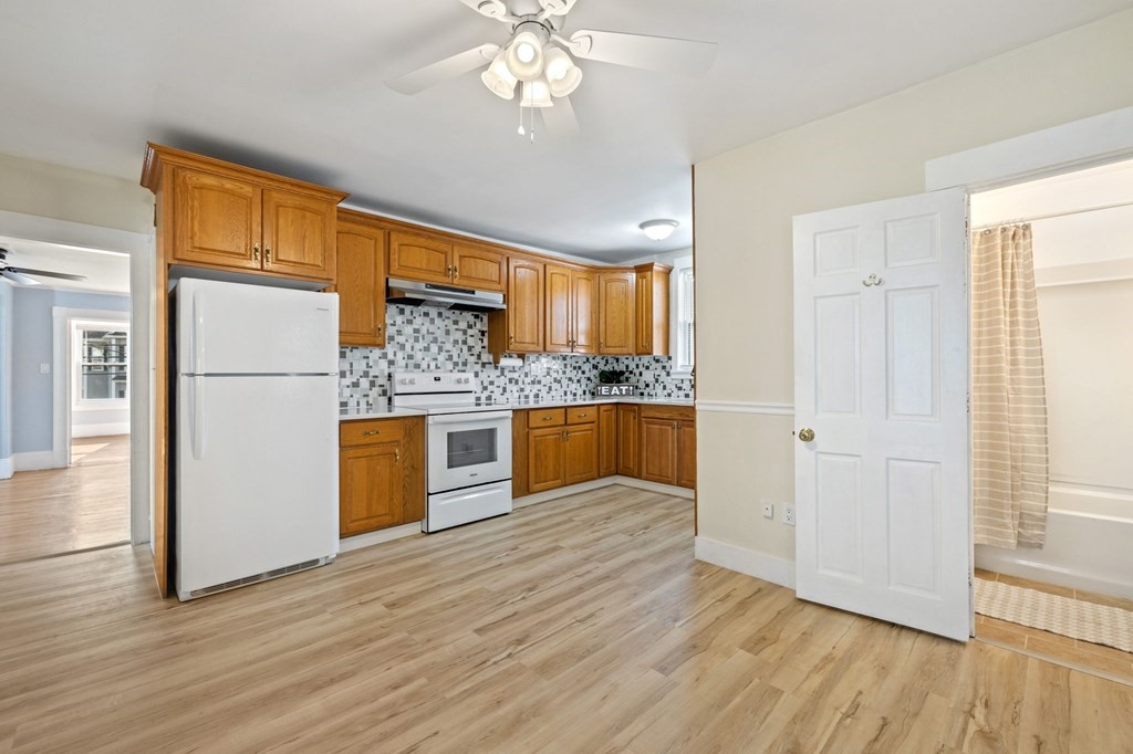 253 Mammoth Road Lowell, MA 01854 - Photo 33 of 42 a kitchen with stainless steel appliances granite countertop a refrigerator a oven a sink with wooden floors and cabinets