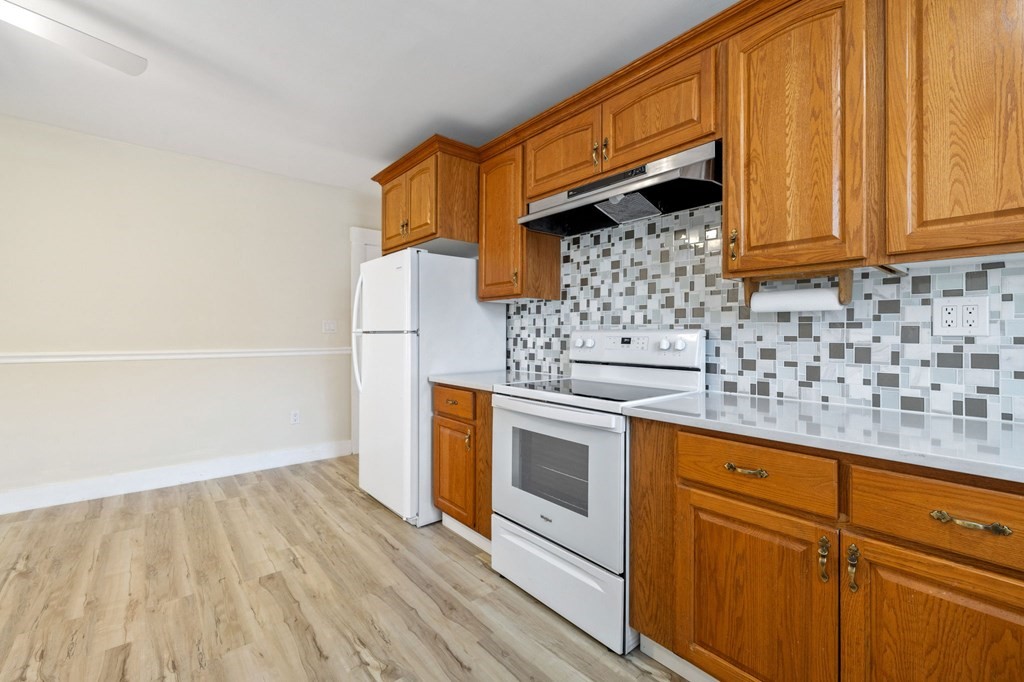 253 Mammoth Road Lowell, MA 01854 - Photo 35 of 42 a kitchen with granite countertop white cabinets and white appliances