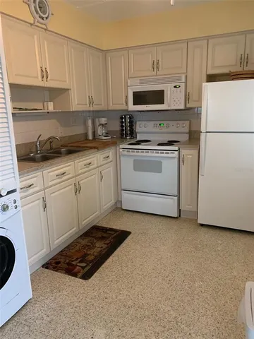 a kitchen with cabinets a sink and white appliances