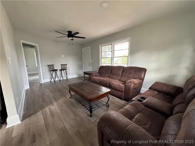 a living room with furniture a ceiling fan and a window