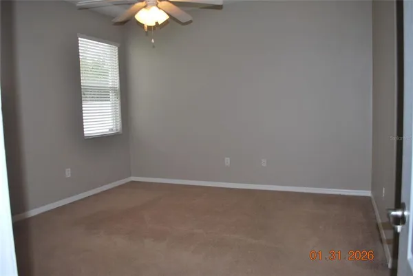 an empty room with windows and fan