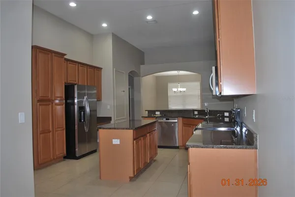 a kitchen with granite countertop a refrigerator stove and sink