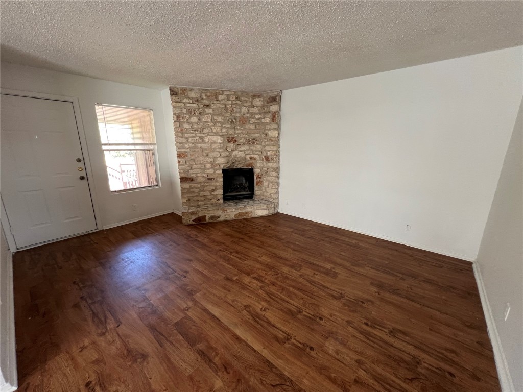 2307 Rachael Court, Unit D Austin, TX 78748 - Photo 6 of 8 Unfurnished living room featuring dark wood-style flooring, a textured ceiling, and a fireplace