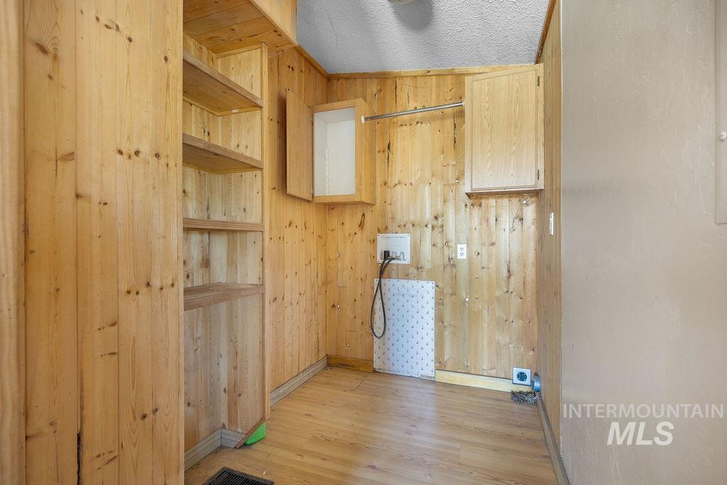 7370 Sagebrush Lane Caldwell, ID 83607 - Photo 17 of 40 Laundry area with washer hookup, light wood-type flooring, wood walls, and a textured ceiling