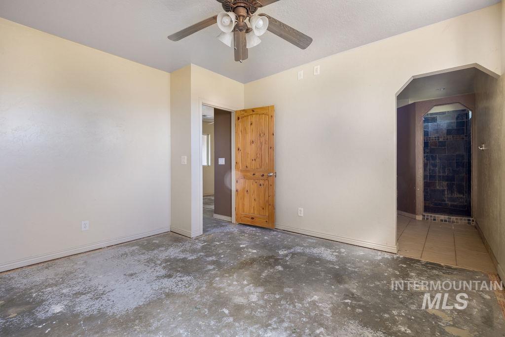 7370 Sagebrush Lane Caldwell, ID 83607 - Photo 21 of 40 Unfurnished bedroom with arched walkways, ceiling fan, ensuite bathroom, and unfinished concrete flooring