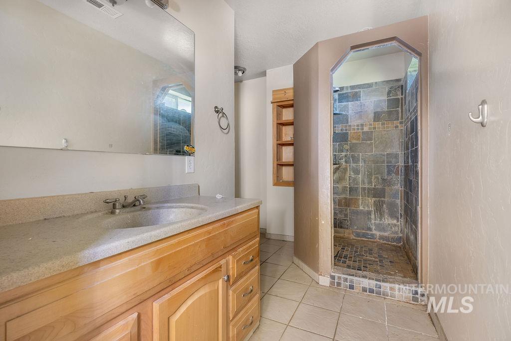 7370 Sagebrush Lane Caldwell, ID 83607 - Photo 22 of 40 Bathroom featuring vanity, a shower stall, light tile patterned floors, and a textured ceiling
