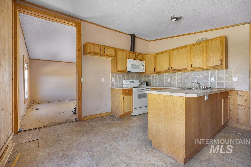 7370 Sagebrush Lane Caldwell, ID 83607 - Photo 23 of 40 Kitchen featuring a textured ceiling, light countertops, white appliances, a peninsula, and backsplash