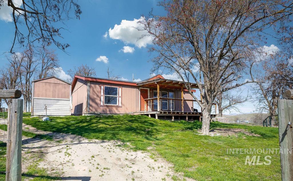 7370 Sagebrush Lane Caldwell, ID 83607 - Photo 25 of 40 Back of house with a yard, a wooden deck, and a storage unit