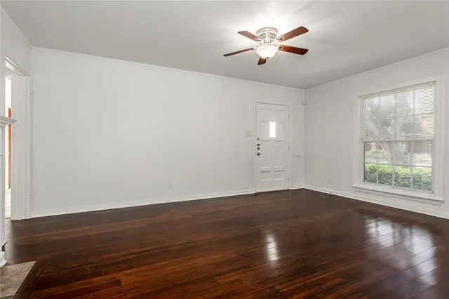 an empty room with wooden floor and chandelier fan